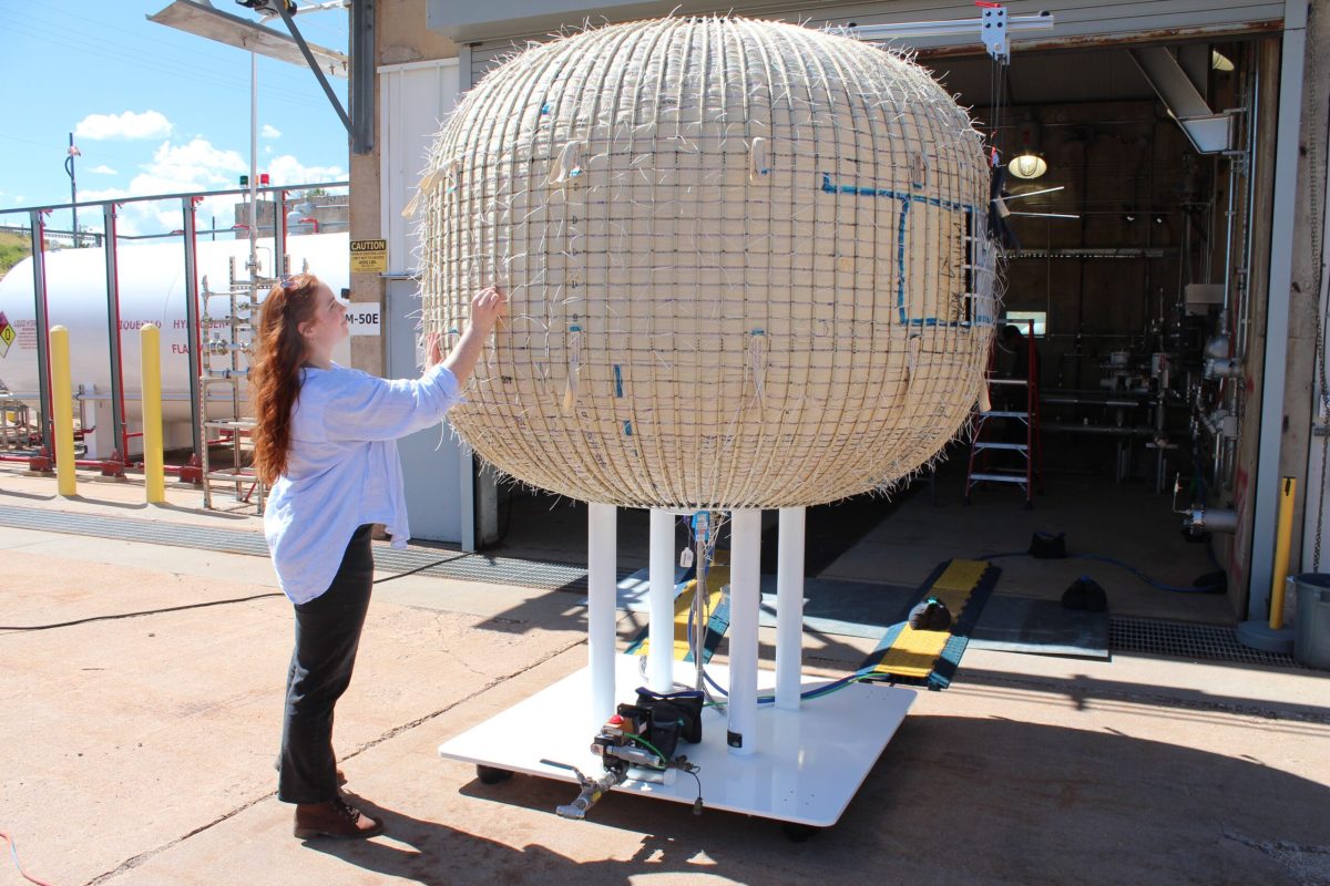 Rowan Palmer, a systems engineer within the Lockheed Martin Space softgoods and habitation team, inspects an inflatable airlock test unit. Credit: Barbara David
